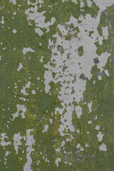 Green peeling paint on the wall. Old concrete wall with cracked flaking paint. Weathered rough painted surface with patterns of cracks and peeling. High resolution texture for background and design.