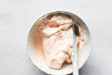 Orange buttercream in a white mixing bowl, American buttercream in a bowl for icing cake, frosting for decorating cake