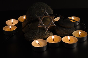 Stones, David star, candles, barbed wire, Israel flag on dark background. Holocaust concept.