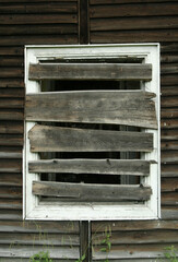 Broken  and boarded up window in worn out ruined old wooden boarding house in spa town.