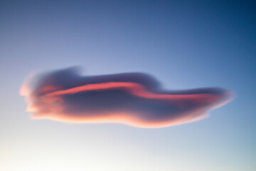 Grey isolated cloud with red wavy line at sunset