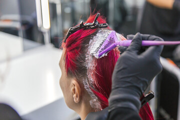 master hairdresser colorist dyes the roots of a woman with red hair - obrazy, fototapety, plakaty