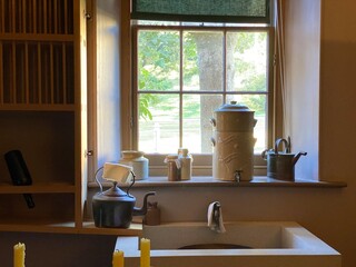 Interior of an old and historical kitchen. Vintage and antique sink, watering can, pots and dishes. Sink under the window.