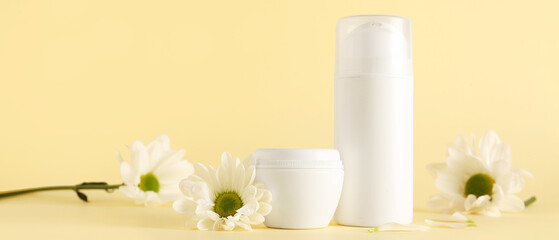 Cosmetic products and chamomile flowers on beige background