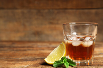 Glass of rum with lime an mint leaves on wooden background