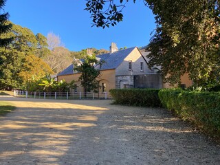 Fototapeta premium Century-old ocre building in the village. Ancient yellow brick house in summer. Antique countryside villa with vegetation.