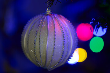 Świąteczna bombka na choince. Boże Narodzenie, Wigilia. Kolorowe krążki świetlme w tle.
