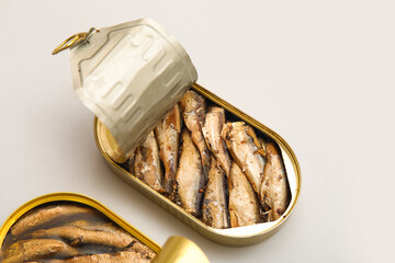 Opened tin cans with sprats in oil on grey background