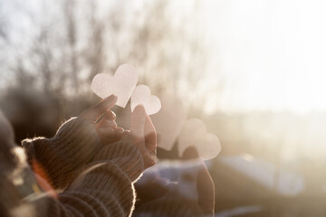 Double exposure of hands with hearts.
