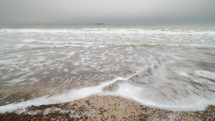 Morze Bałtyckie zimą. Śnieg pokrywa wydmy i rudawozłotą trawę. Mglisty horyzont. Długi czas...
