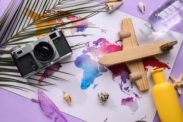 Fototapeta na wymiar Composition with world map, bottle of sunscreen cream, wooden plane and photo camera on purple background