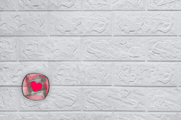 Romantic template with copy space. Glass with heart inside on background of white brick wall....