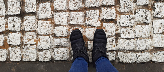 Banner with legs in snowboots. View from above. Feet in winter shoes on white bricks background....