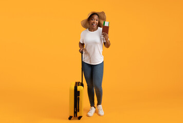 Happy black tourist lady holding flight ticket with suitcase, studio