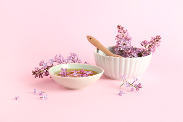 Bowl of honey with lilac twigs and flowers on pink background