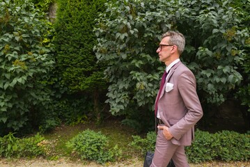 Naklejka na ściany i meble Man in a suit walking through the park