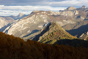 Landscape of Peaks of Europe national park at sunset with bright sunset sky and autumn forest with colorful yellow and orange leaves