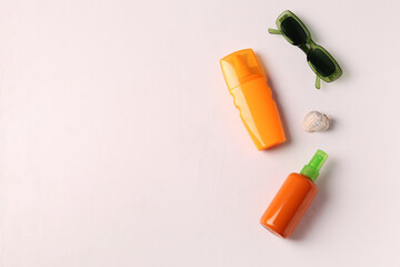 Bottles of sunscreen cream and sunglasses on white background