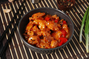 Bowl with tasty sweet and sour chicken on table, closeup
