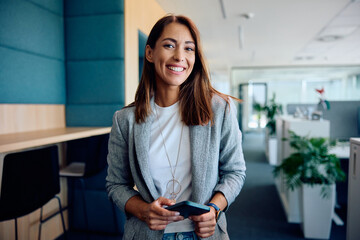 Young happy businesswoman in office looking at camera.