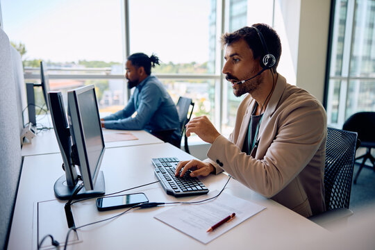 Customer support representative working on desktop PC in office.
