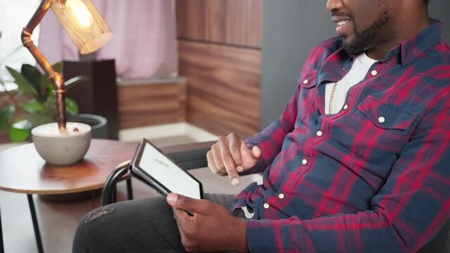 male internet user watching website of online store on tablet screen, swiping pages of catalog