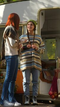 The modern hippie style shines as chic young women unwind in an autumn camp with a trailer.