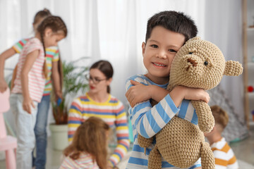 Cute little Asian boy with toy bear in kindergarten