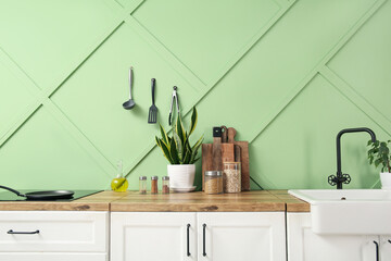 Wooden countertop with houseplant, cutting boards, jars and utensils