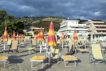 Fototapeta na wymiar Beach with umbrellas and beach chairs, urban landscape, southern seaside town, family vacation, vacation, background, selective focus