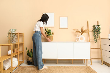 Woman putting houseplant on white dresser in room