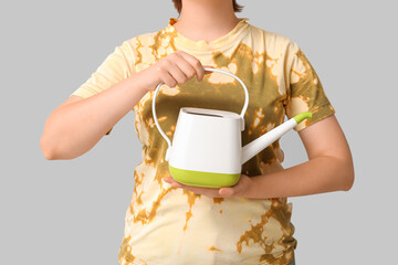 Woman with watering can on grey background