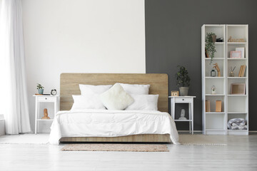 Interior of modern bedroom with white bed and alarm clock on bedside table - obrazy, fototapety, plakaty