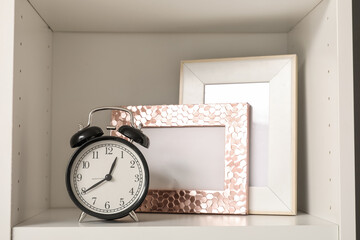 Alarm clock and photo frames on shelf, closeup