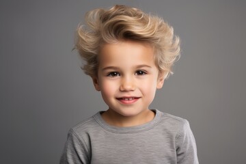 Portrait of a cute little boy with blonde hair on grey background