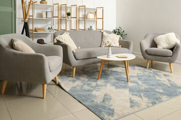 Interior of modern living room with stylish carpet, grey sofa, coffee table and armchairs