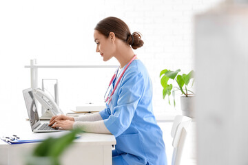 Female medical intern working with laptop in clinic