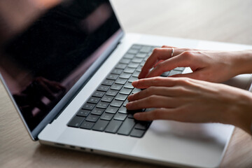 A close-up view of a womans hands typing swiftly on a laptop keyboard, capturing the essence of modern professional productivity.