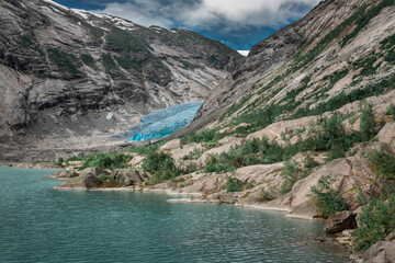 Blue glacier ice of Nigardsbreen in Norway, with lake and mountains