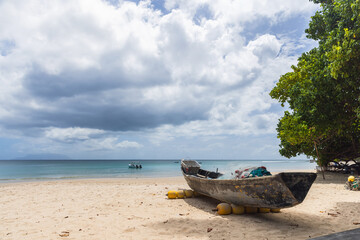Small old fishing boat lays on white sand of Beau Vallon Beach, Seychelles