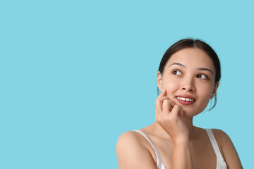Fototapeta premium Beautiful young Asian woman on blue background