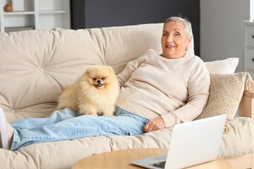 Senior woman with Pomeranian dog lying on sofa at home