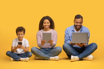 Family Gadgets. Black parents and little son using different electronic devices