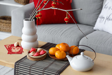 Coffee table with tangerines, fortune cookies, teapot and Chinese lanterns in festive living room....