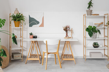 Interior of light room with workplace, plants and shelf units