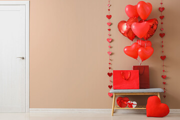 Grey bench with shopping bags and heart-shaped balloons near beige wall. Valentine's Day celebration