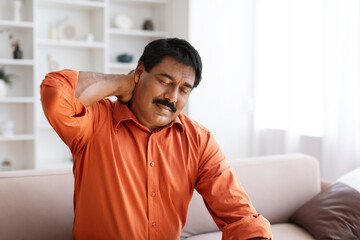Suffering middle aged indian man feeling neck pain