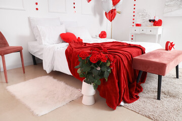 Vase with beautiful red roses in festive bedroom. Valentine's Day celebrations