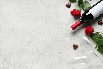 Bottle of wine with glasses, chocolate candies and red roses on white background. Valentine's Day celebration