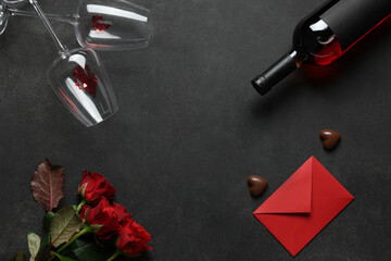 Bottle of wine with glasses, chocolate candies, envelope and red roses on black background. Valentine's Day celebration